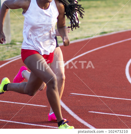 Female sprinters running during a track and field race 102473210