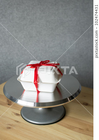 Pastry metal turntable for cakes on wooden table with red ribbon cake bento packaging Pastry metal turntable for cakes on wooden table with red ribbon cake bento packaging 102474431