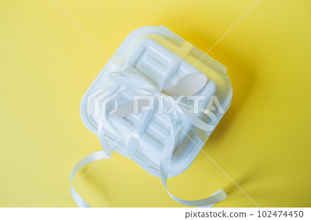 A bento cake box with a wooden spoon stands closed on a yellow background A bento cake box with a wooden spoon stands closed on a yellow background 102474450