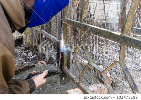 welder welds door hinge to new gate post welder welds door hinge to new gate post 102475189