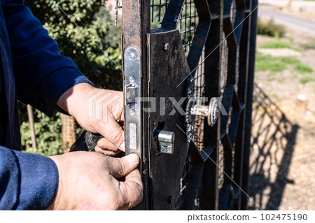 worker changes cylinder of door lock outdoors 102475190