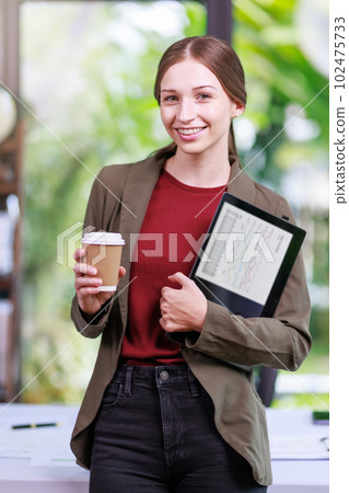 Concept of business office woman working,Businesswoman smile while working about her invesment plan with analyzing document and business investment graph data by using laptop on desk in workstation. 102475733