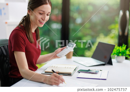 Concept of business office woman working,Businesswoman smile while working about her invesment plan with analyzing document and business investment graph data by using laptop on desk in workstation. Concept of business office woman working,Businesswoman smile while working about her invesment plan with analyzing document and business investment graph data by using laptop on desk in workstation. 102475737