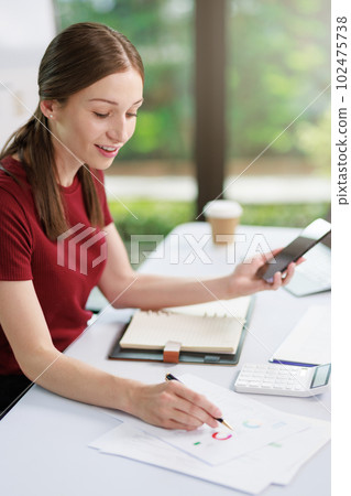 Concept of business office woman working,Businesswoman smile while working about her invesment plan with analyzing document and business investment graph data by using laptop on desk in workstation. 102475738