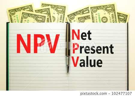 NPV net present value symbol. Concept words NPV net present value on white note on a beautiful background from dollar bills. Pen. Business and NPV net present value concept. Copy space. 102477107