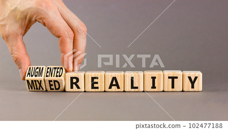 Augmented or mixed reality symbol. Concept words Augmented reality Mixed reality on wooden cubes. Beautiful grey background. Businessman hand. Business augmented or mixed reality concept. Copy space. 102477188