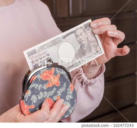 [一位家庭主婦從釦子裡拿出一張 10,000 日元的鈔票] 102477243