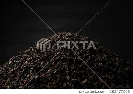 A pile of black fanning or broken loose leaf tea on a dark black background. Close-up, side view. A pile of black fanning or broken loose leaf tea on a dark black background. Close-up, side view. 102477606
