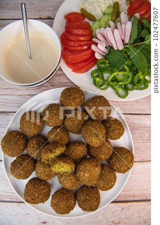Fried falafel balls and tahini sauce with chopped legumes and chickpeas Fried falafel balls and tahini sauce with chopped legumes and chickpeas 102477607
