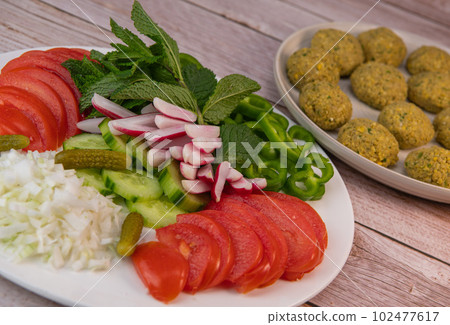 Plate of fresh vegetable salad, tomato, cucumber, onion, gherkin, radish, mint leaves and falafel Plate of fresh vegetable salad, tomato, cucumber, onion, gherkin, radish, mint leaves and falafel 102477617