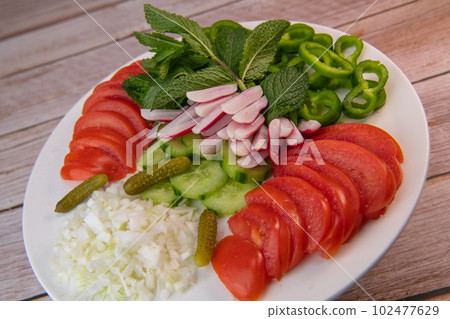 Plate of fresh vegetable salad, tomato, cucumber, onion, gherkin, radish, mint leaves on turntable Plate of fresh vegetable salad, tomato, cucumber, onion, gherkin, radish, mint leaves on turntable 102477629
