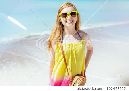 Portrait of happy girl in sunglasses at beach in colorful dress 102478322