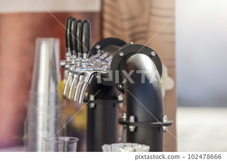Handmade beer faucet. Bar counter in a pub with a beer tap, side view. The concept of buying, selling and drinking beer. Handmade beer faucet. Bar counter in a pub with a beer tap, side view. The concept of buying, selling and drinking beer. 102478666