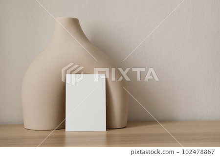 Modern wedding stationery. Closeup of blank greeting card, invitation mockup. Beige boho ceramic vase, geometric sculpture. Contemporary neutral branding still life. Trendy boho style. Modern organic 102478867