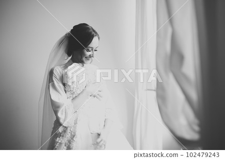 Beautiful bride wearing fashion wedding dress with feathers with luxury delight make-up and hairstyle, studio indoor photo shoot Beautiful bride wearing fashion wedding dress with feathers with luxury delight make-up and hairstyle, studio indoor photo shoot 102479243