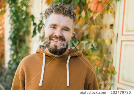 Close up shot of curly European male with beard wears switshot outdoors. Handsome man with crisp light hair. 102479720