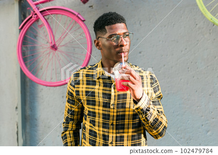 Young cheerful african american male on city having fun and holding cocktail. Man on summer holiday. Leisure lifestyle holiday and summer drinks concept 102479784