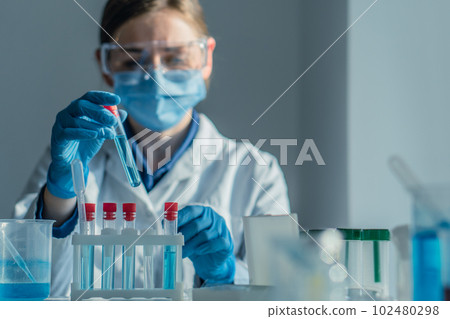 Scientist in biotechnological laboratory is researching new methods treating diseases. Laboratory assistant in a medical laboratory performs blood test to determine level various biological substances Scientist in biotechnological laboratory is researching new methods treating diseases. Laboratory assistant in a medical laboratory performs blood test to determine level various biological substances 102480298