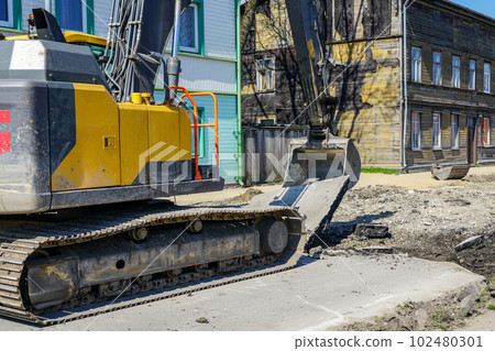 Crawler excavator use bucket to breaks up the old asphalt layer during street reconstruction Crawler excavator use bucket to breaks up the old asphalt layer during street reconstruction 102480301