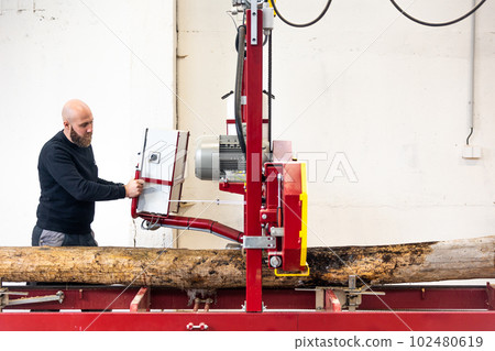 Professional carpenter cutting raw wood on the table with electric band saw, cutting wooden board at sawmill, carpentry manufacturing concept Professional carpenter cutting raw wood on the table with electric band saw, cutting wooden board at sawmill, carpentry manufacturing concept 102480619