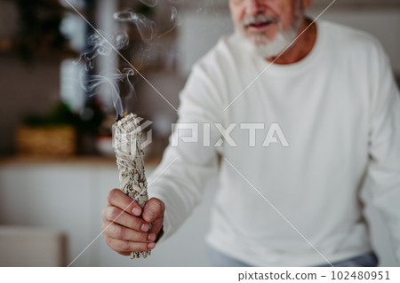 Senior man doing ritual with a sage. Senior man doing ritual with a sage. 102480951