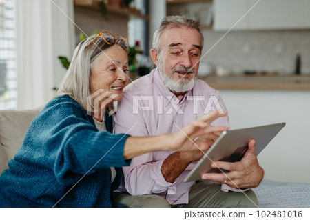Senior couple scrolling tablet in their livingroom. Senior couple scrolling tablet in their livingroom. 102481016