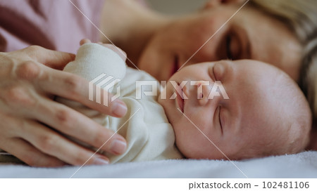 Mother cuddling with her newborn baby in their bed. 102481106