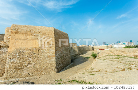 Ruins of Qalat al-Bahrain portuguese fortress with downtown in the background, Manama, Bahrain 102483155