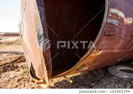 Old rusty water tower lying on the ground with its lid torn off Old rusty water tower lying on the ground with its lid torn off 102483244