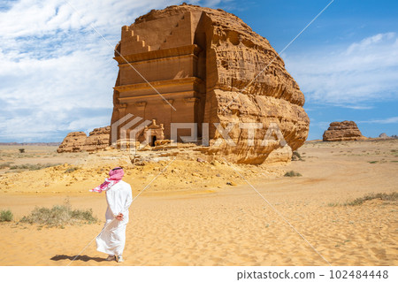 Arab man in front of Tomb of Lihyan, carved in rock in desert,  Mada'in Salih, Hegra, Saudi Arabia 102484448