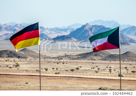 German and Kuwaiti flags waving togetner on the wind in Saudi Arabian desert, Al Ula, Saudi Arabia 102484462