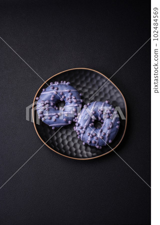 Delicious sweet donut of purple color in glaze and with lilac balls 102484569