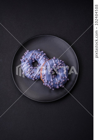 Delicious sweet donut of purple color in glaze and with lilac balls 102484588