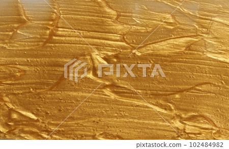 Sample of golden glitter gel with small particles, texture of highlighter cosmetics, lipstick, blush 102484982