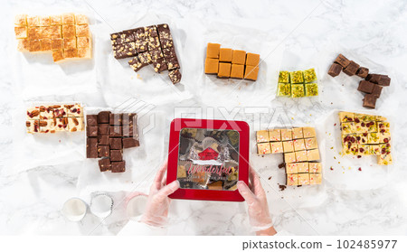 Flat lay. Packaging a homemade variety of fudge for Christmas food gifts into tin boxes. 102485977