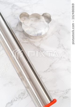 Rolling cookie dough and cutting out panda-shaped shortbread cookies. 102486069