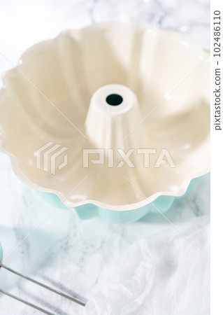 Greasing bunt cake pan to bake pumpkin bunt cake. 102486110