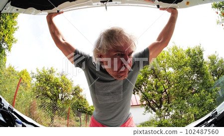 Funny confused driver opens the hood of a broken car. Stressful technical issue concept Funny confused driver opens the hood of a broken car. Stressful technical issue concept 102487560