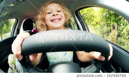 Fisheye lens portrait of a funny smiling blonde girl pretending to drive a car 102488769