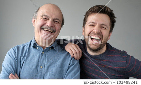 Happy mature senior father and grown son standing together, hugging, looking at camera 102489241