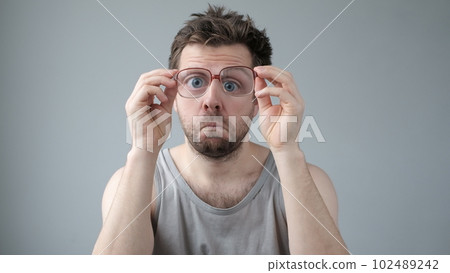 Surprised man in big glasses with WOW expression on gray backgound 102489242