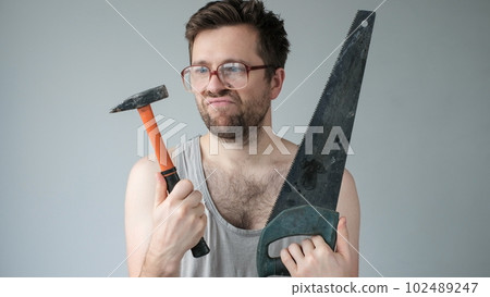 Young caucasian worker man holding a hammer isolated on grey background 102489247