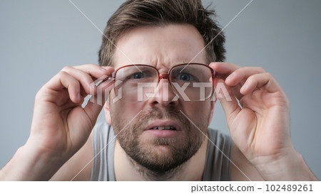 Surprised man in big glasses with WOW expression on gray backgound 102489261