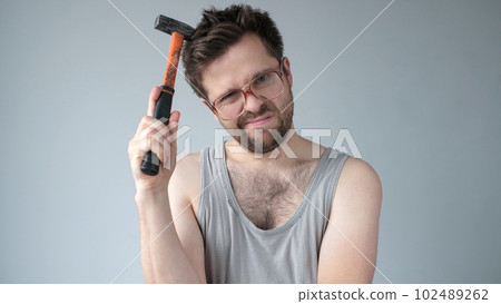 Young caucasian worker man holding a hammer isolated on grey background 102489262