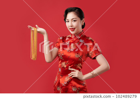 Chinese new year festival, Beautiful Young asian woman wearing traditional cheongsam qipao dress with gold necklaces on red background, 102489279