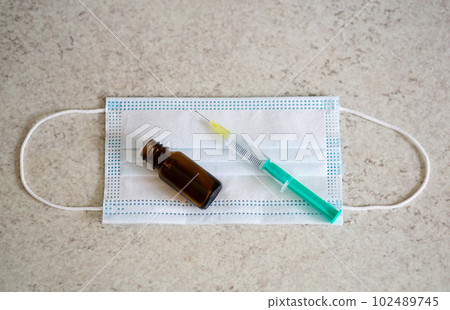 Medical bottle, syringe and face mask on the table with copy space. Vaccination session. Medical bottle, syringe and face mask on the table with copy space. Vaccination session. 102489745