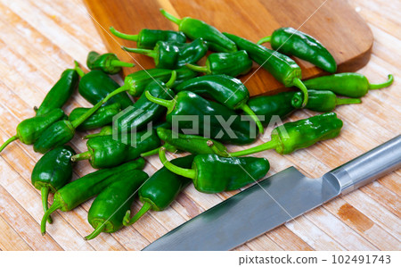 Fresh green padron peppers on wooden cutting board 102491743