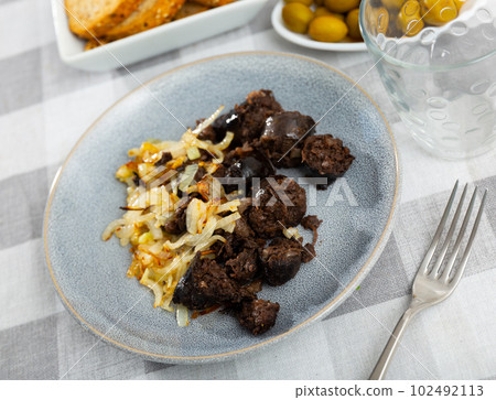 Morcilla con cebolla - fried blood sausage with onion on table Morcilla con cebolla - fried blood sausage with onion on table 102492113