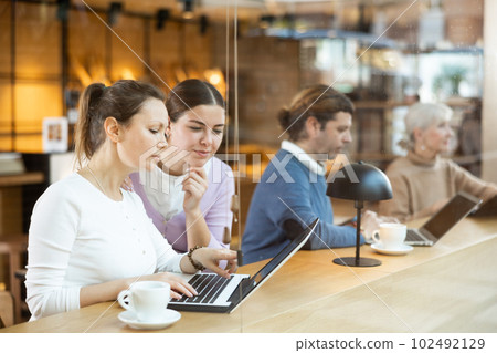 Female designers sitting in cafe with laptop and coffee 102492129