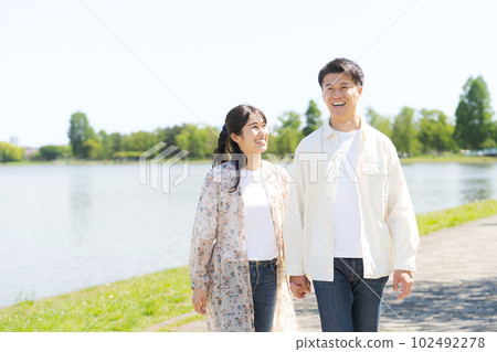 Portrait of man and woman walking by the pond 102492278